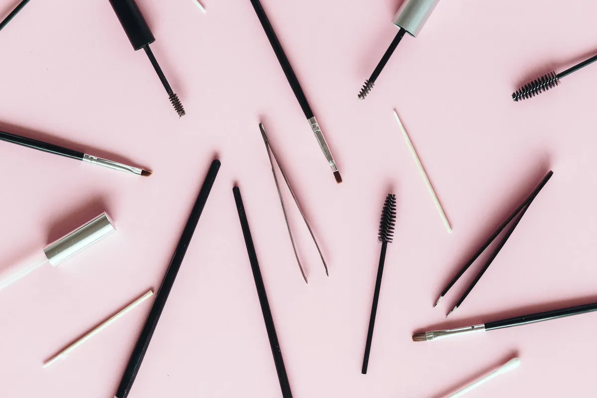 Goupillons, pince et pinceaux de beauté du regard sur fond rose poudré