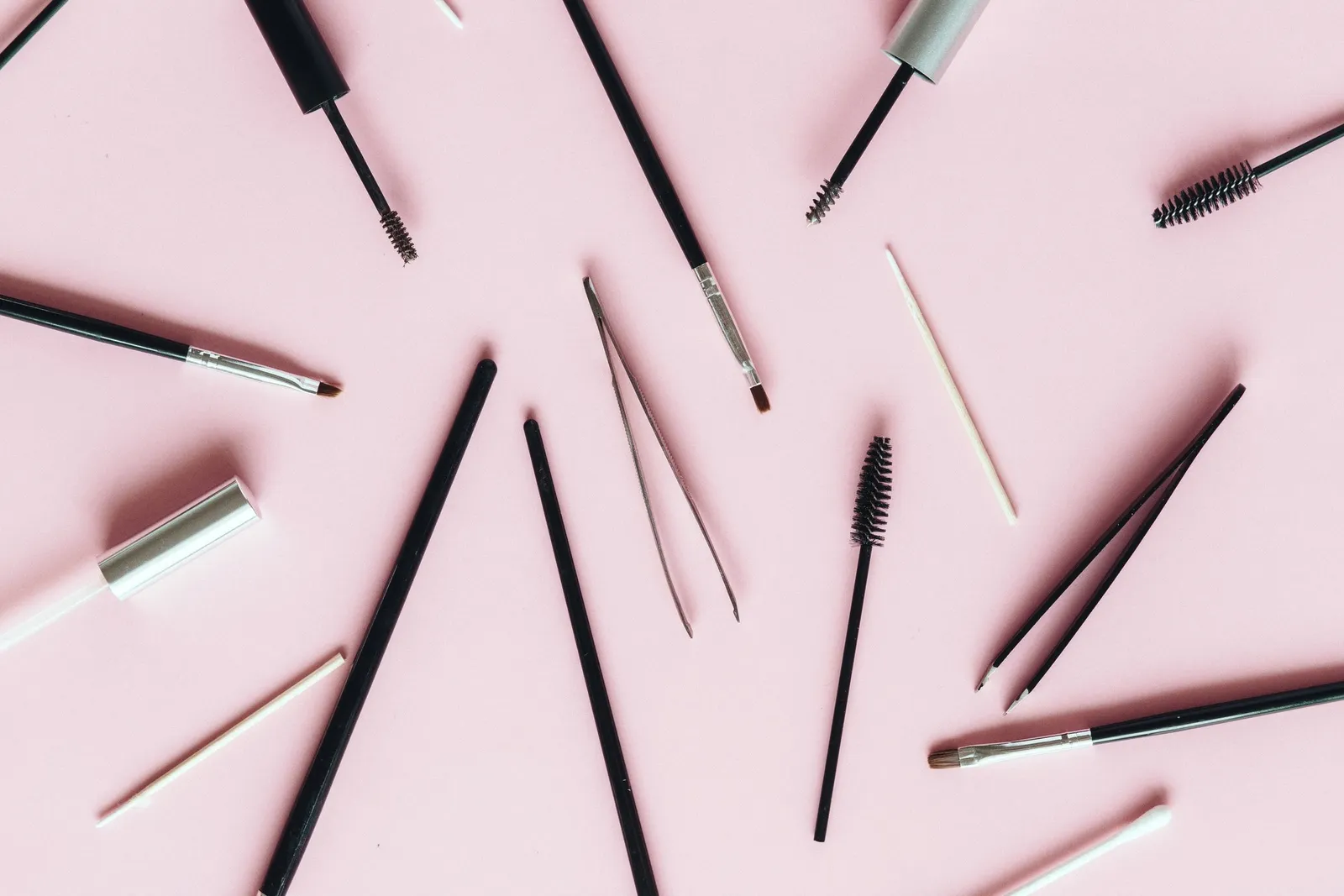Goupillons, pince et pinceaux de beauté du regard sur fond rose poudré